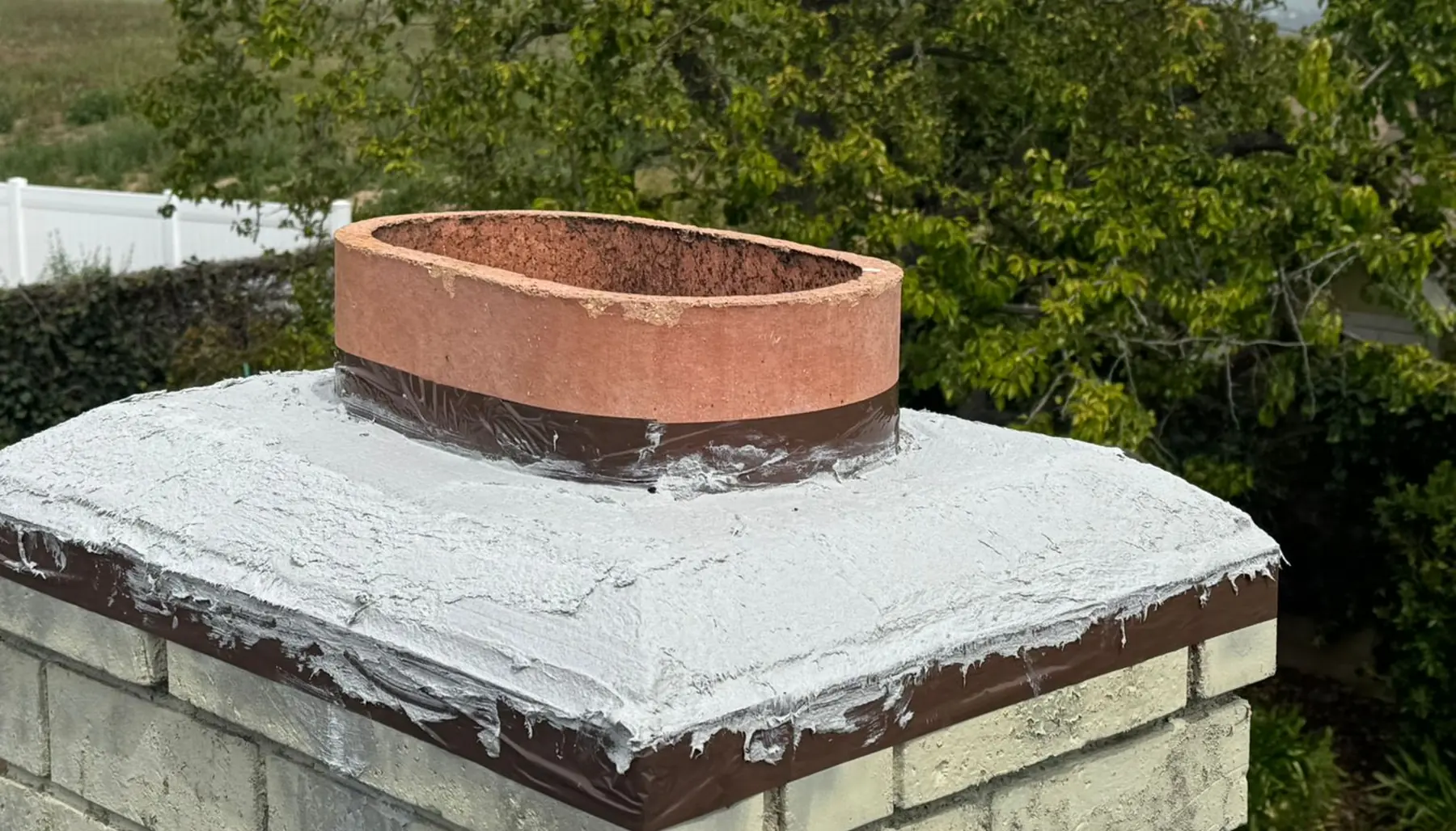 Chimney crown with a fresh protective coat, seen from the roof with trees behind