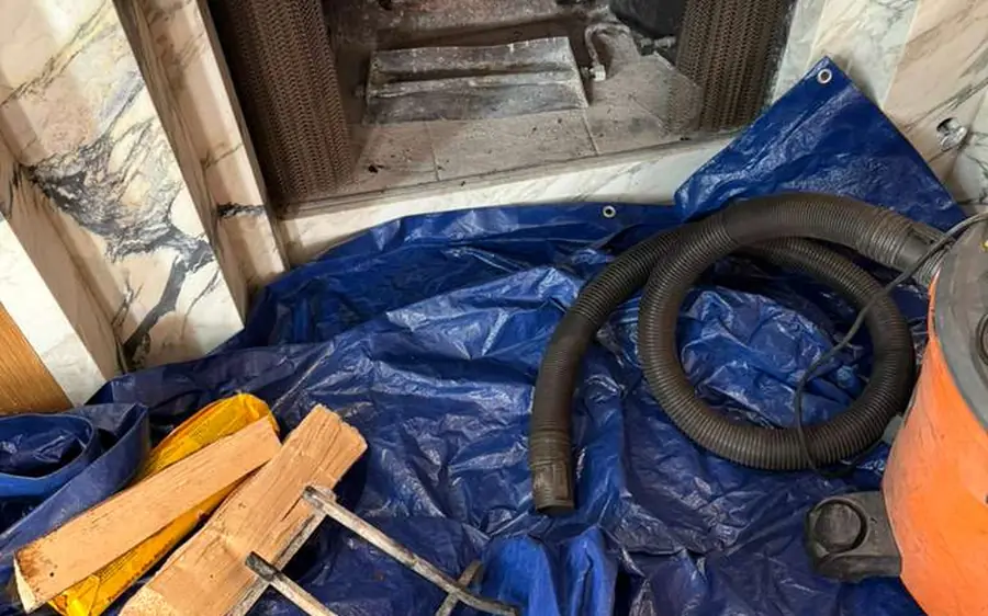 Fireplace prepared for a chimney sweep with floor protection, vacuum and rods